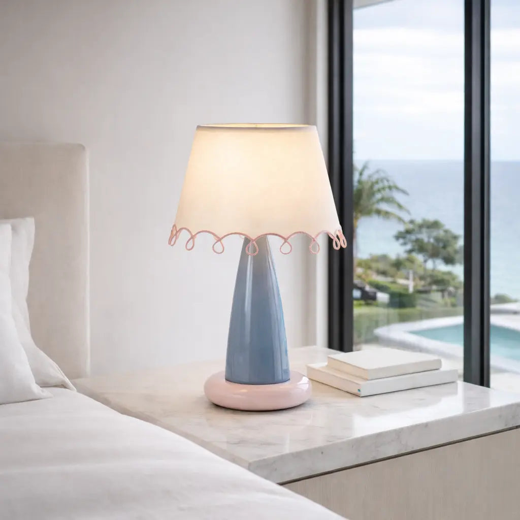 Lampe de table en céramique bleue et rose avec abat-jour beige sur table de nuit