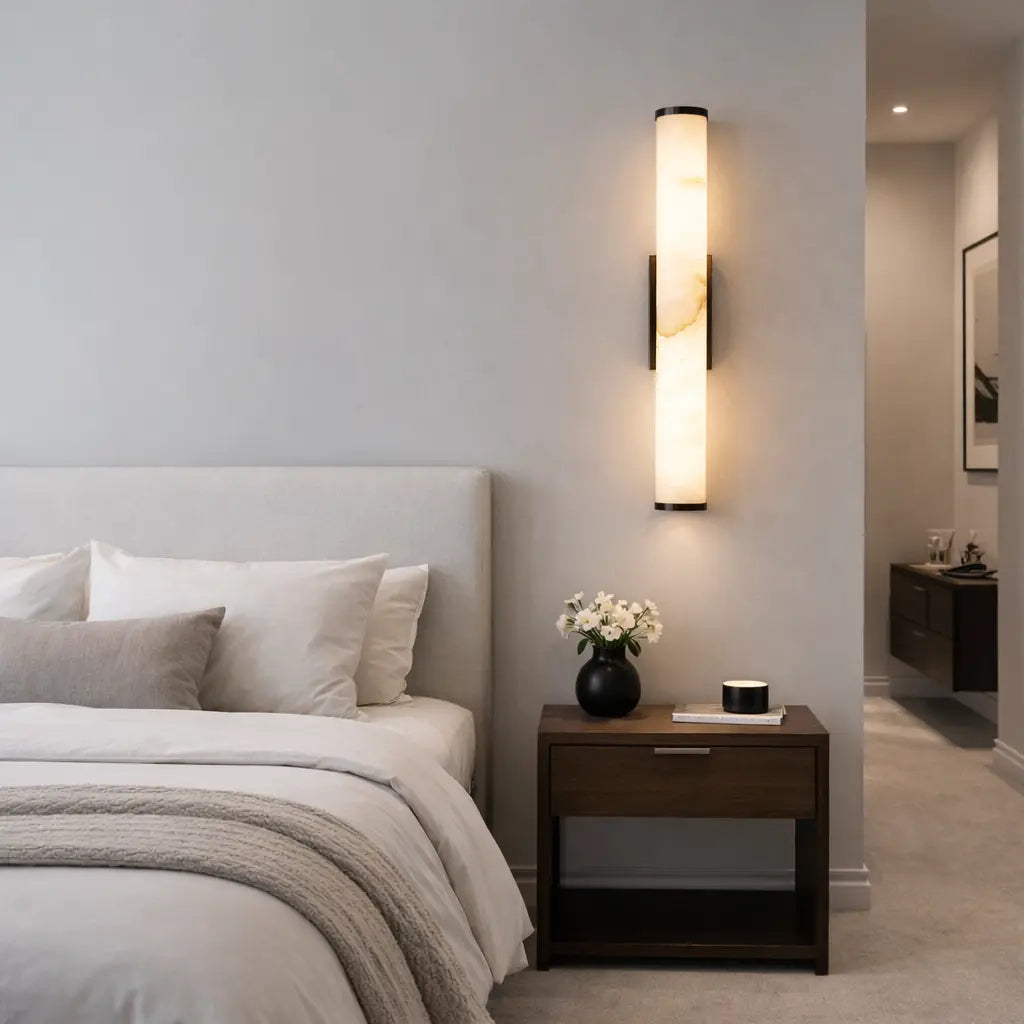 Applique murale LED en albâtre beige effet marbre et métal bronze installée verticalement dans une chambre moderne